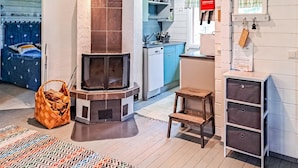 A compact living space with a built-in fireplace, a small kitchen area, and a bedroom with a bed and a patterned rug. - Pilkkaniemi by Interhome (Juuka)