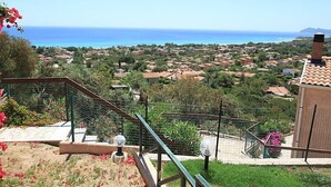 Un quartier résidentiel avec vue sur la mer, un escalier menant à un balcon et un petit bâtiment doté d’un toit en tuiles.