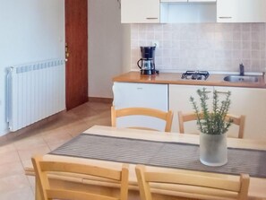 A compact kitchen with a coffee maker, a small refrigerator, and a sink. There is a dining table with chairs and a potted plant. - Apartment Jasen by Interhome (Pula/Krnica)
