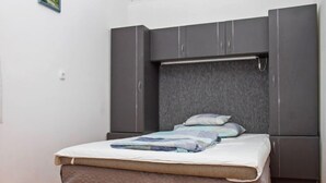Ein Schlafzimmer mit einem Bett, einem grauen Kleiderschrank und einem Vorhang.
