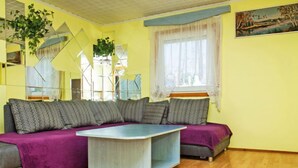 Ein Wohnzimmer mit einem Ecksofa, einem Couchtisch und einem großen Fenster mit Vorhängen.