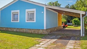 Einbungalow mit blauer Fassade und überdachter Veranda.