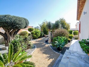 Un jardín con diversas plantas y un sendero de piedra que lleva a un edificio.