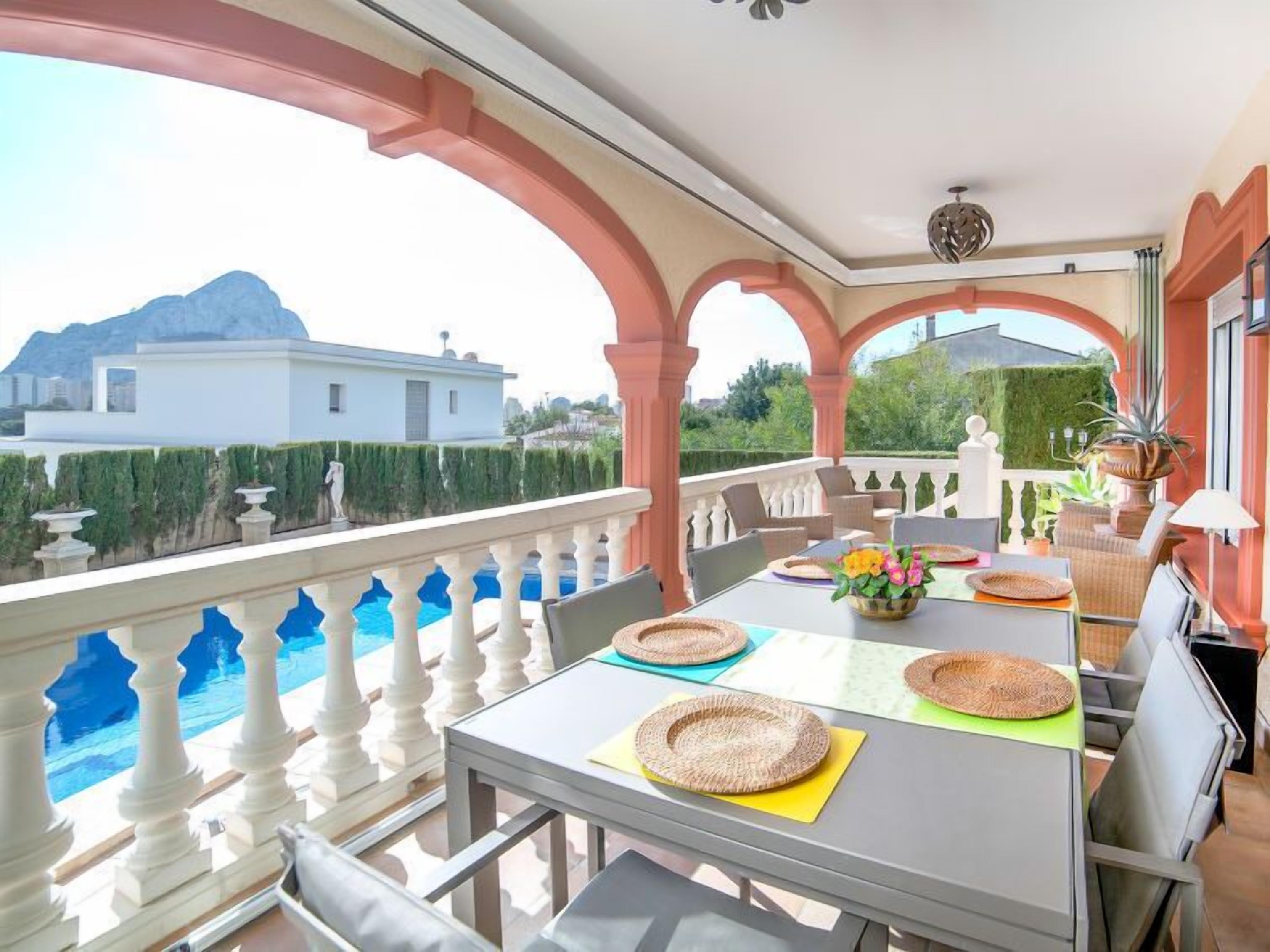 A balcony with a pool, outdoor seating, and a view of a mountain.