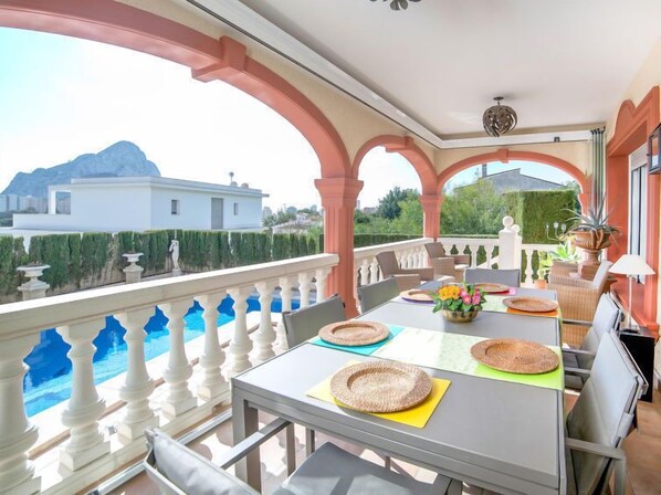 A balcony with a pool, outdoor seating, and a view of a mountain.