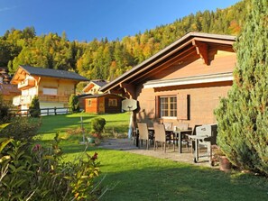A chalet-style building with a patio area, surrounded by a forested hillside. - Chalet Lorila by Interhome (Villars)