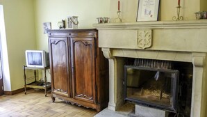 Ein Zimmer mit Kamin, einem Holzkabinett und einem Fernseher auf einem Schrank.