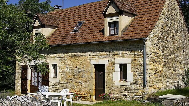 Ein Haus aus Stein mit Ziegeldach, zwei Fenstern und einer Tür.