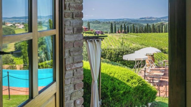 A room with a large window overlooking a vineyard and a pool. - Casa Mori by Interhome (Certaldo)