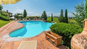 A swimming pool with a tiled deck, surrounded by greenery and a clear sky. - Casa Mori by Interhome (Certaldo)