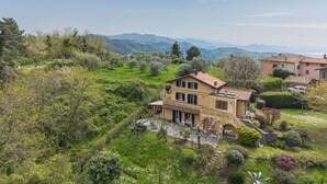 Une villa située sur une colline, avec un jardin, une vue sur les montagnes et un ciel dégagé.