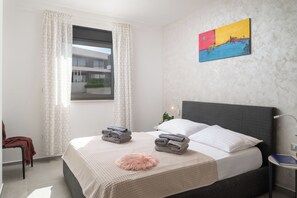 A hotel room with a bed, a window with curtains, a painting on the wall, and a small bedside table. - Villa Fasana by Interhome (Fažana)