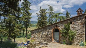 A stone building with a wooden door, surrounded by trees and a grassy area. - Le Bonatte by Interhome (Radda in Chianti)