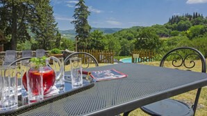 A table set outdoors with clear glasses, a red drink, and a menu. - Le Bonatte by Interhome (Radda in Chianti)