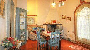 A cozy dining area with a wooden table, blue chairs, and a stone fireplace. - Le Bonatte by Interhome (Radda in Chianti)