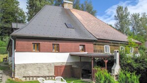 A two-story house with a sloped roof, a chimney, and a covered patio area with outdoor furniture. - Lenora I by Interhome (Lenora)