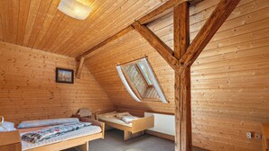 A cozy attic bedroom with wooden walls, a sloped ceiling, two single beds, a window, and a radiator. - Lenora I by Interhome (Lenora)