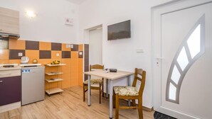 A small kitchenette with a refrigerator, microwave, and coffee maker. There is a dining area with a table and chairs, and a TV mounted on the wall. - Apartment B&B by Interhome (Medulin/Ližnjan)