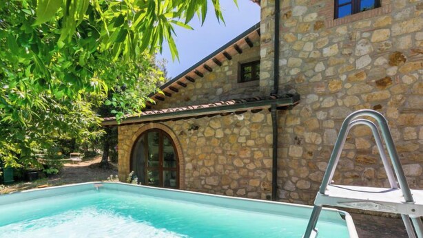 Um edifício de pedra com piscina, escada e céu azul límpido.