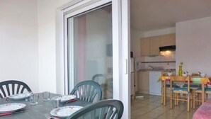 Un'area pranzo con tavolo apparecchiato per quattro persone, sedie e una porta scorrevole in vetro che dà su una cucina.