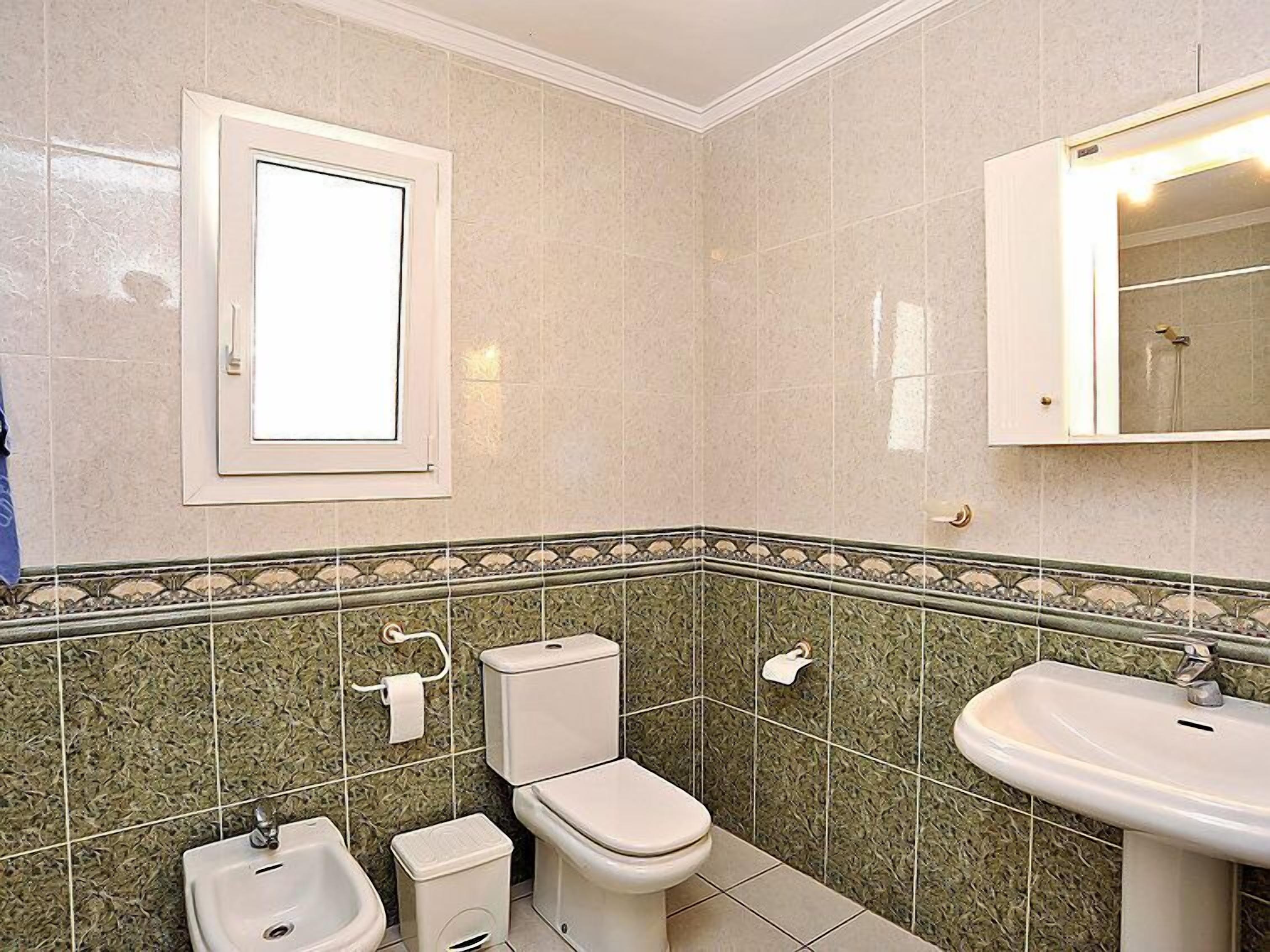 Une salle de bain équipée de toilettes, d’un bidet, d’un lavabo et d’un miroir.