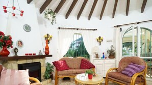 Ein gemütliches Wohnzimmer mit Kamin, Korbmöbeln und Blick auf Grünflächen.