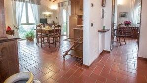 Ruime eethoek met een houten tafel en stoelen, een keuken met houten kastjes en een betegelde vloer.