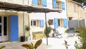 Un edificio con persiane blu, una panchina e una sedia nel cortile.