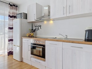 Eine moderne Küche mit weißen Schränken, einem Edelstahlkühlschrank, einem Backofen und einer Kaffeemaschine.