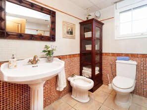 Une salle de bain avec un lavabo blanc, un meuble en bois, des toilettes et un miroir.