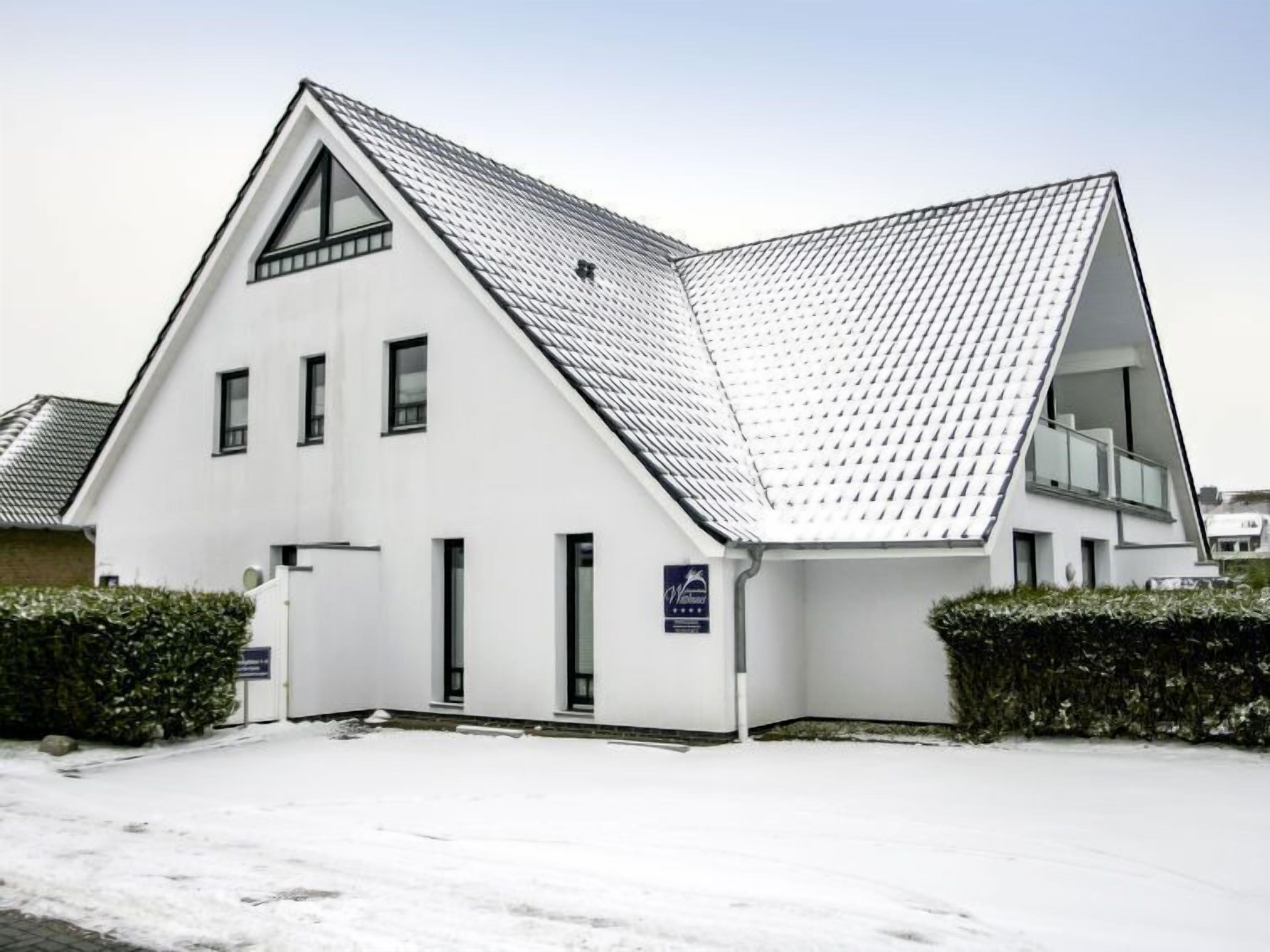 A modern white building with a triangular roof and multiple windows.