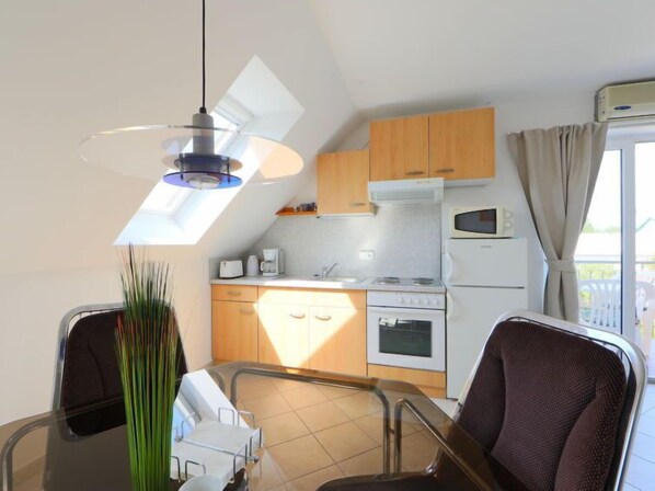 Uma cozinha compacta com área de jantar, uma luminária no teto e vista para o exterior.