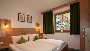 A double bed with a wooden headboard, two bedside tables, and a window with curtains. - s´ HimmelReich by Interhome (Längenfeld)
