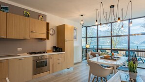 A modern kitchen with wooden cabinets, a stove, and a dining area with a table and chairs.