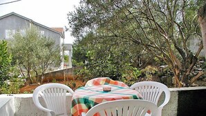 A patio with two white plastic chairs and a table covered with a plaid tablecloth. - Apartment Zdenko by Interhome (Ugljan/Kali)