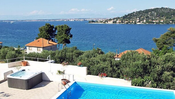 A pool with a view of the sea, surrounded by greenery and buildings. - Apartment Zdenko by Interhome (Ugljan/Kali)