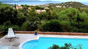 A pool with a view of a coastal town and hills.