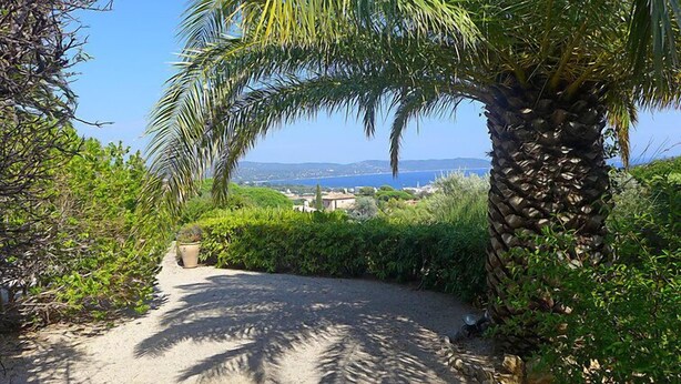 A pathway leading to a scenic overlook with a view of the sea and distant hills.
