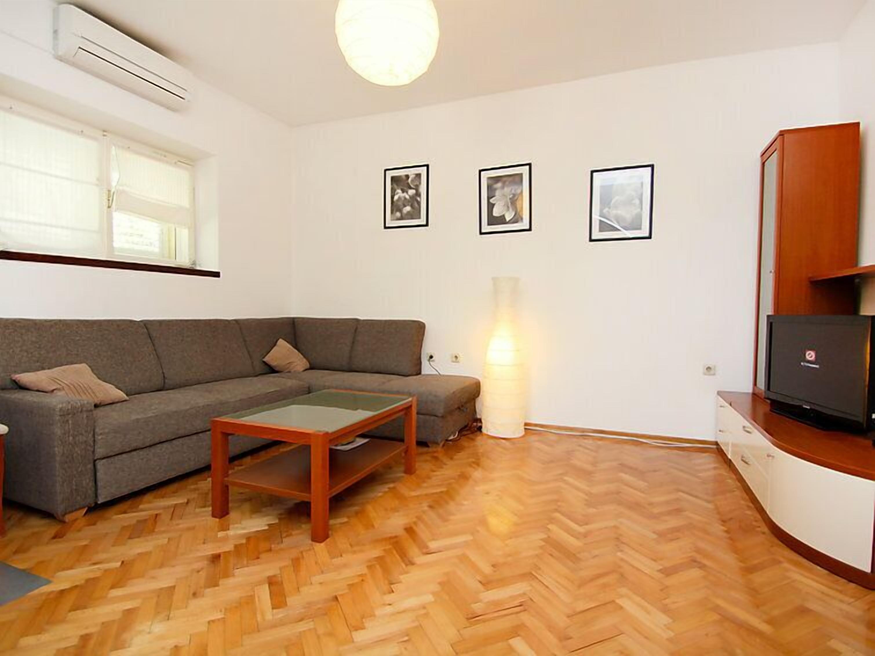 A living room with a sofa, a coffee table, a TV on a cabinet, and a lamp.