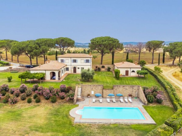 Une grande villa dotée d’une piscine, entourée de jardins et d’arbres parfaitement entretenus.