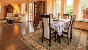 A dining area with a table set for four, surrounded by chairs, a floral tablecloth, and a patterned rug.