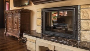 A fireplace with a stone surround, a television mounted above it, and a wooden cabinet to the left.