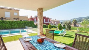 Une terrasse avec une table dressée pour les repas, une piscine et une vue sur le quartier.