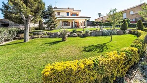 Une maison à deux étages avec un patio et un jardin bien entretenu.
