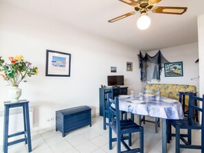 A dining area with a table set for four, a ceiling fan, and a vase of flowers.