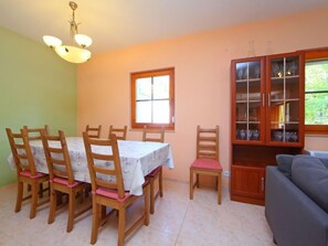A dining area with a table and chairs, a cabinet with glass doors, and a window.
