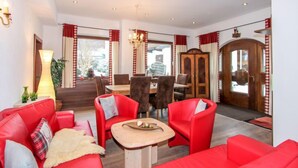 Una sala de estar moderna con sofás rojos, una mesa de centro de madera y un comedor con un aparador de madera y cortinas rojas.