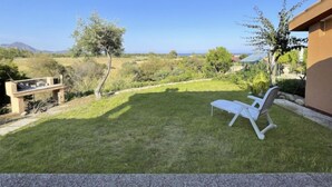 Un patio trasero con césped, una silla de descanso blanca y vistas al campo y a las montañas.