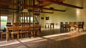 Un vaste espace dédié à la salle à manger, doté de meubles en bois et d’un plafond haut avec des poutres apparentes.