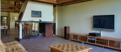 A spacious living room with a fireplace, a television, and a chess table.
